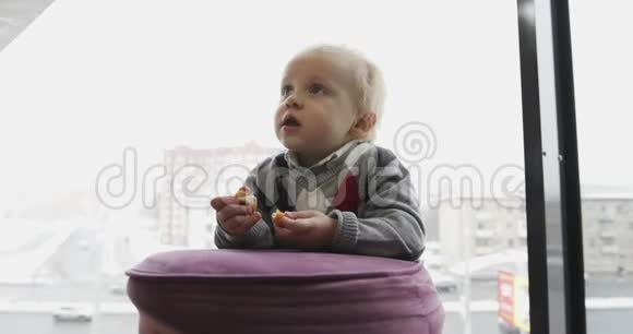 一个小孩子正在大窗户的背景上吃鸡排视频的预览图