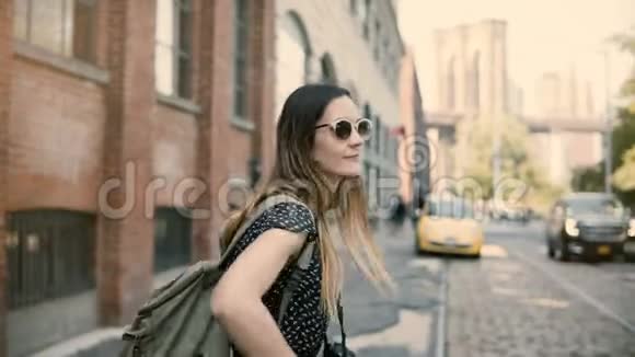 镜头跟随快乐兴奋的欧洲旅游女孩背包和相机戴着太阳镜微笑转身4K视频的预览图