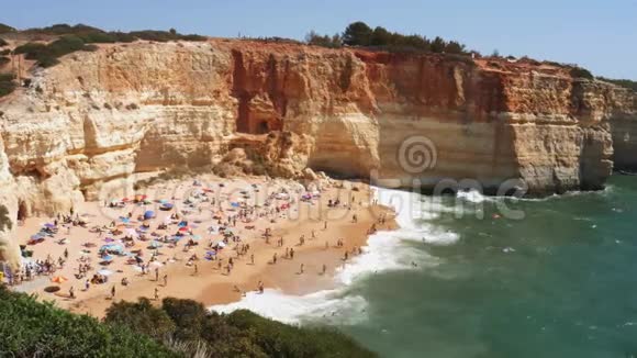 葡萄牙拉戈亚阿尔加维贝纳吉尔海滩金色悬崖繁忙海滩和绿松石海洋的高视角景观视频的预览图