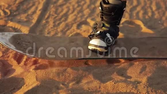 沙板沙板雪板女孩尝试一个新的板揉她的腿近距离沙漠视频的预览图