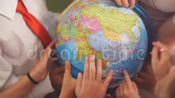 小学生和老师一起看地球仪上的地理课视频的预览图
