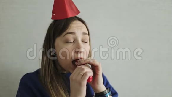 一位戴着节日礼帽的成年妇女在室内充气一个红色气球视频的预览图