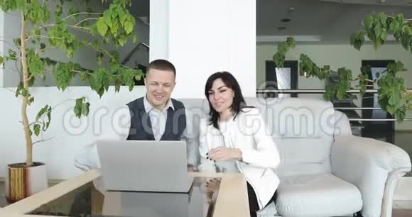 一对迷人的夫妇正坐在大厅的沙发上讨论一笔生意视频的预览图