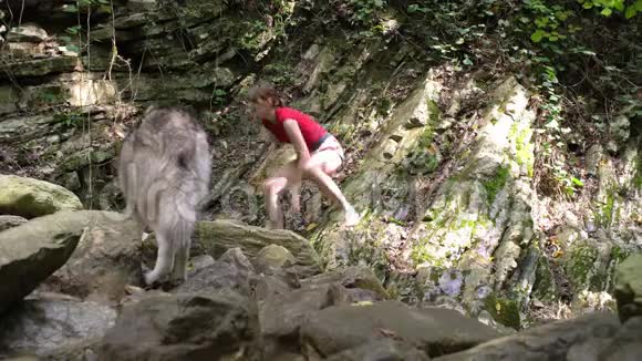 光着脚的女孩带着跛脚的狗在河边的树林里散步视频的预览图