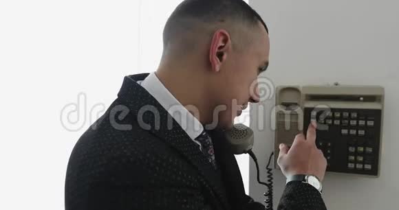 一个穿西装的年轻商人用一部老式手机在办公室进行内部交流视频的预览图