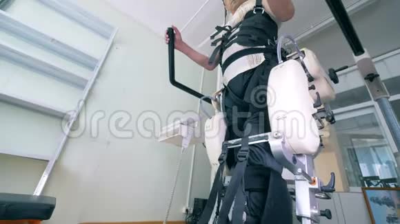 有身体障碍的男性患者正在步行轨迹模拟器上锻炼电子医疗机器人视频的预览图