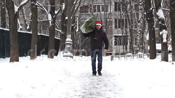 一个戴着红色圣诞帽的人带着一棵圣诞树装在刚刚在圣诞市场买的格子里慢动作视频的预览图