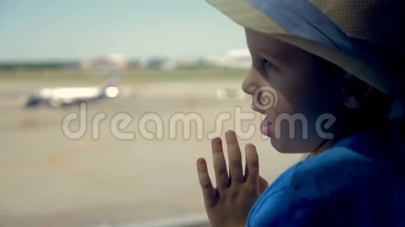 小男孩靠近窗户关门一个男孩透过大窗户看跑道上的飞机视频的预览图