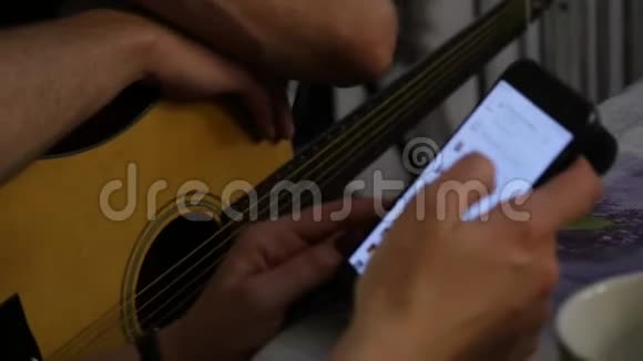 特写双手练习弹吉他双手拿着手机4K视频的预览图