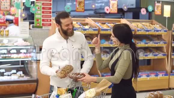 一对年轻夫妇的肖像超市里有一辆装满产品的手推车视频的预览图