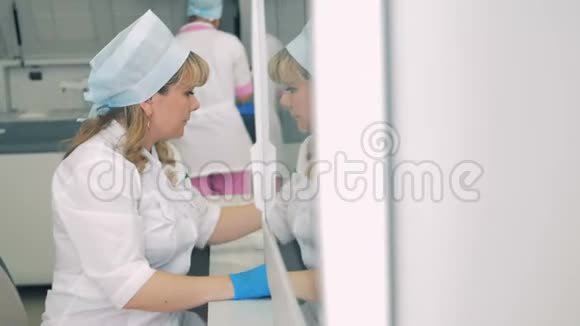 实验室里的人用设备工作女工人坐在桌子旁而一个医疗离心机旋转视频的预览图