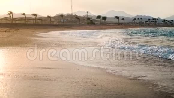 在沙滩上翻滚的海浪上拍摄的令人惊叹的日落4K镜头视频的预览图