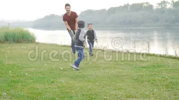 家庭和儿童的概念快乐的父亲和两个儿子在夏天公园玩得开心视频的预览图