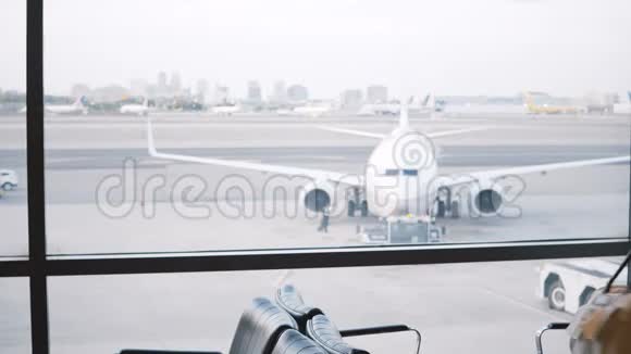 欧洲女游客走到机场休息室候机室窗口放下她的包看着飞机经过视频的预览图