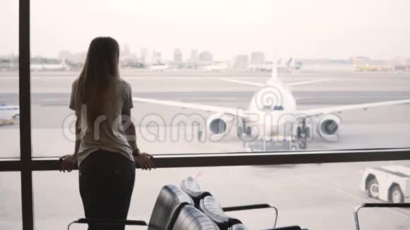 年轻的欧洲女商人站在机场候机厅窗口看看和使用智能手表视频的预览图