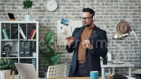 戴着耳机的男人在办公室跳舞听着音乐享受工作休息视频的预览图