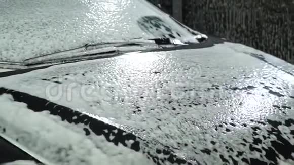 洗车洗车机清洗汽车车上覆盖着白色的冲洗泡沫特写镜头视频的预览图