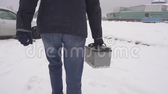 一个人在车里搬运和安装一个汽车电池冬天雪慢动作视频的预览图