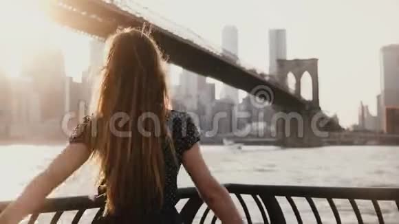 在纽约布鲁克林大桥附近站在河堤旁的女孩被风吹过手臂张开视频的预览图