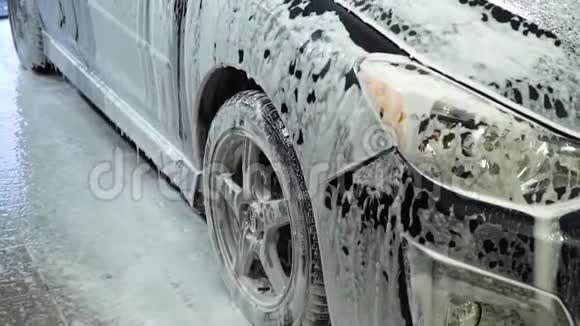 洗车洗车机清洗汽车车上覆盖着白色的冲洗泡沫特写镜头视频的预览图