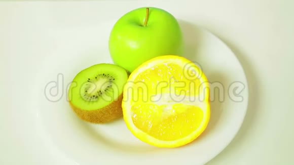 白色盘子里的橙皮猕猴桃和绿皮苹果的两半旋转成一个圆圈视频的预览图