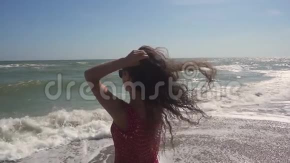 一个女人在大海的背景下在风中长出头发后景慢动作视频的预览图