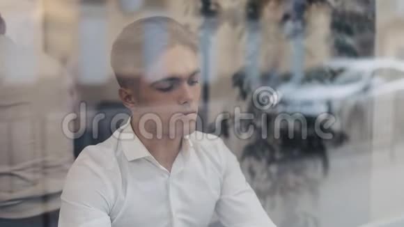 一个疲惫的年轻商人坐在咖啡馆的一张桌子旁用笔记本电脑工作自由职业者沟通IT疲惫视频的预览图