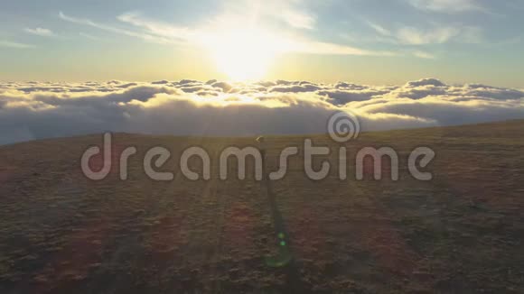 女人在云上奔跑向着太阳和山的边缘举起双手空中景观视频的预览图