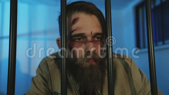 一个留着胡须的无家可归的人站在监狱的炉栅后面看着警察视频的预览图
