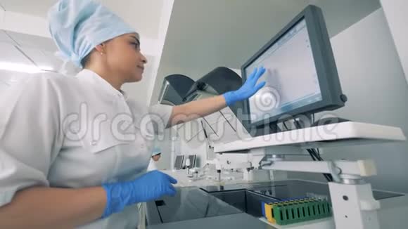 一名护士在实验室里与一个带有现代自动化医疗设备的监视器一起工作视频的预览图