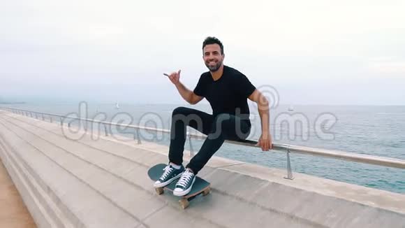 滑板运动员坐在现代城市的海露台上玩滑板视频的预览图