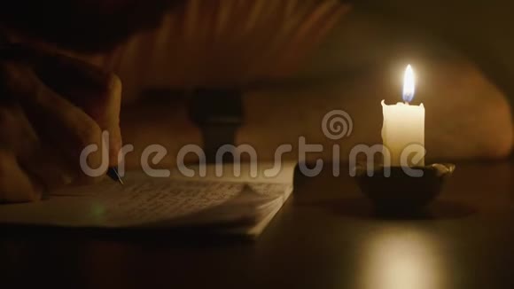 在昏暗的房间里用笔在烛光下写字视频的预览图
