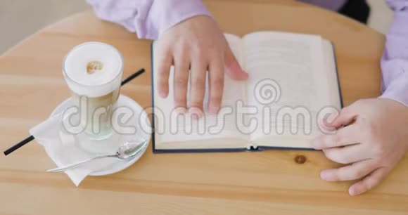 男人正在看一本书手指在书页上坐在咖啡屋里喝着一杯卡布奇诺视频的预览图