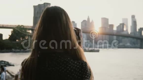 后景妇女与相机拍摄惊人的布鲁克林大桥日落城市景观全景在纽约市4K视频的预览图