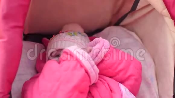 小婴儿躺在婴儿车里穿着夹克和帽子和他的母亲在街上散步视频的预览图