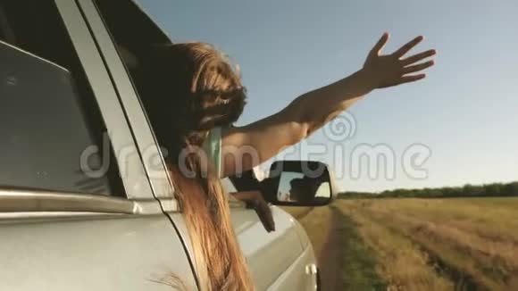 手从车窗里抓住风长发女孩坐在汽车前座上伸出手臂视频的预览图