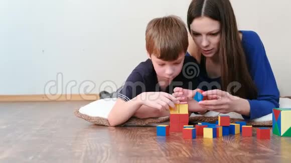 妈妈和儿子一起玩木制彩色教育玩具积木躺在地板上他们建了一个红色的盒子视频的预览图