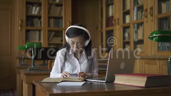 年轻漂亮的女人在研究话题坐在桌子上手提电脑在图书馆视频的预览图