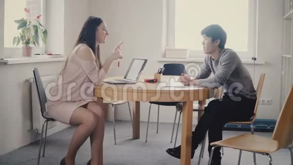 迷人的快乐女领导听亚洲男同事混合族裔的商人在阁楼办公室工作视频的预览图