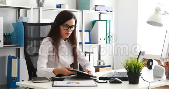 女商人戴着黑色眼镜在现代办公室里填写文件在笔记本电脑上工作视频的预览图