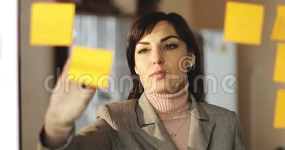 中年商务妇女正在办公室的玻璃上贴小贴纸视频的预览图