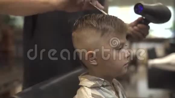 理发店里有吹风机的男孩发型理发店的儿童理发理发师发型小男孩与视频的预览图