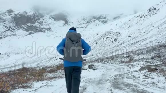 一位游客沿着白雪覆盖的小路散步一个人走在雪地里在高山上远足视频的预览图