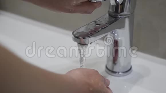 一个女孩的特写她的手用水龙头里的水冲洗她的手慢动作视频的预览图