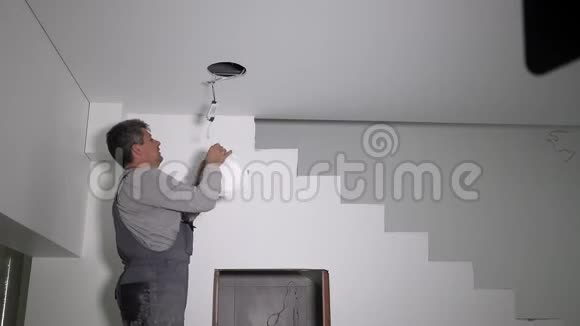 电工连接电线将LED灯安装到天花板上视频的预览图