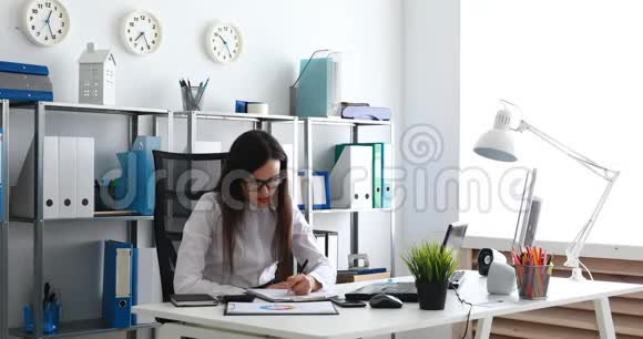 女商人摘下眼镜用手擦脸在现代办公室填写文件视频的预览图