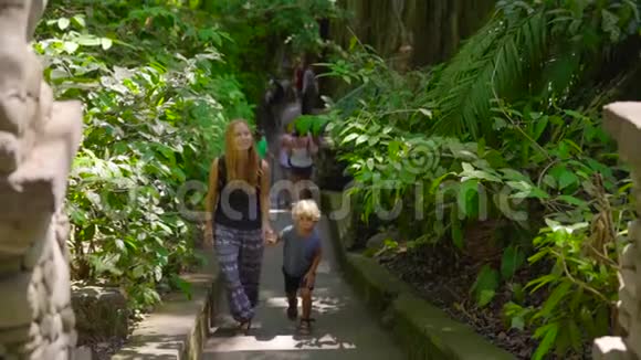 一名年轻女子和她的小儿子在印度尼西亚乌布德的猴子森林生态公园中慢镜头拍摄视频的预览图