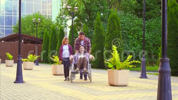 十几岁的女孩和一个男人在公园里抱着一个坐轮椅的残疾妇女慢节奏视频的预览图