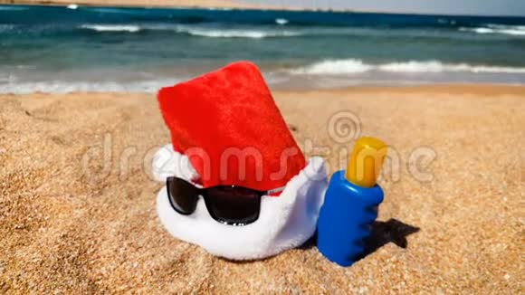 圣诞老人帽子躺在沙滩上的4K镜头在热带岛屿庆祝圣诞节的概念视频的预览图