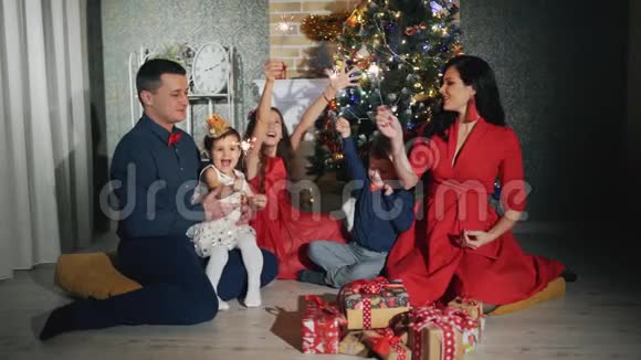 幸福的家庭有五个人他们都在微笑看着圣诞树脚下的摄像机视频的预览图
